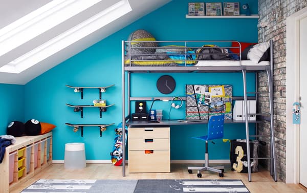 A teenage room with a silver-coloured loft bed with a desk and chest of drawers underneath.