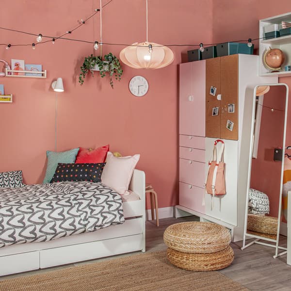 A teen's bedroom with painted walls has a wardrobe, standing mirror, footstools, and an extendable bed that comes with storage.