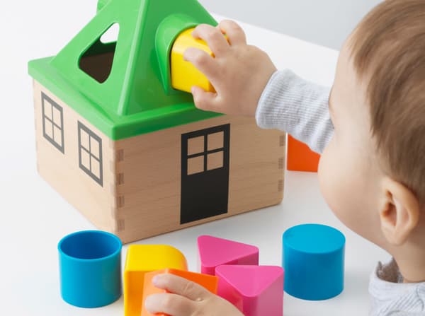 A toddler playing with an IKEA toy made from wood and colourful but BPA-free plastic parts.