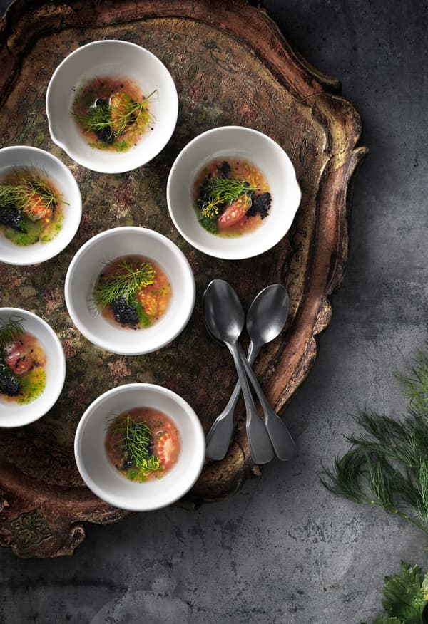 A tomato dish garnished with parsley and served in small white stoneware bowls on a tray, seen from above.