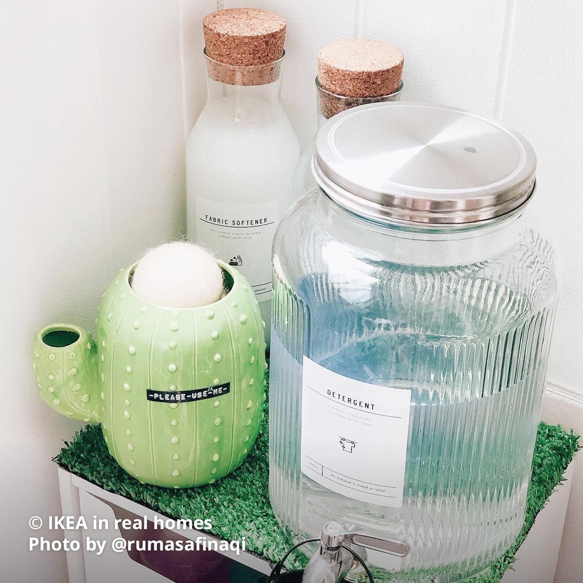 A top angled view of the shelving at the service yard area with VARGAGEN jar with tap, two bottle of IKEA 365+ carafe with stopper and a cactus looking vase containing linen balls. Photo by instagrammer @rumasafinaqi for IKEA in real homes ©