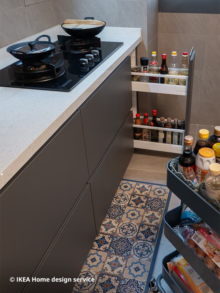 A top view of a pull-out drawer in the base cabinet of IKEA METOD kitchen system along with the hob. On the bottom right corner sits a grey-blue RÅSKOG trolley.