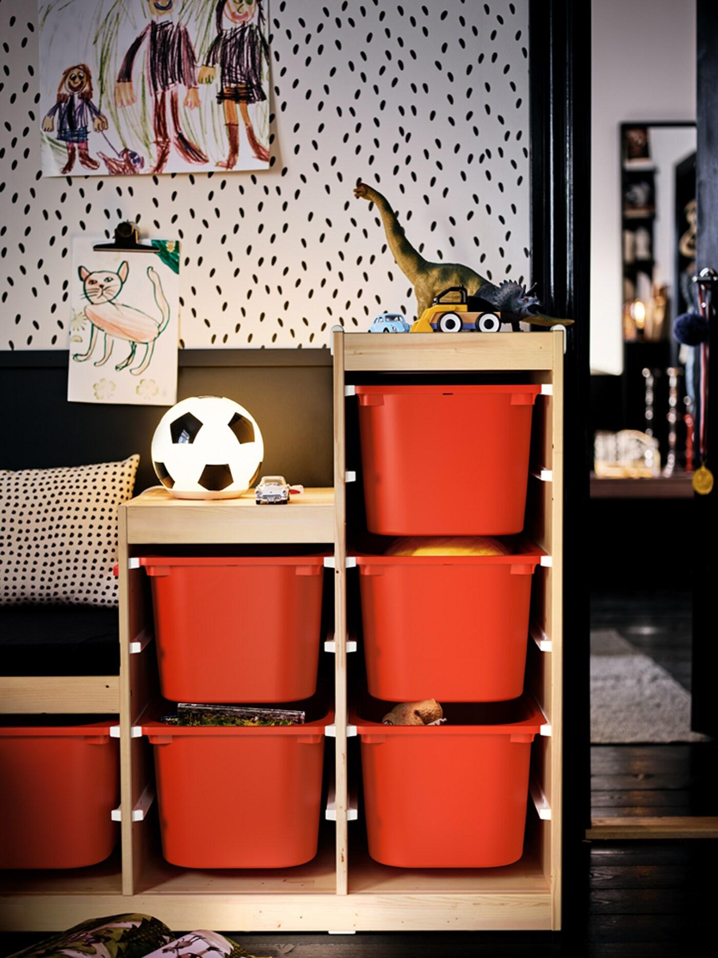 A toy-filled TROFAST unit with orange storage boxes in a kids’ room set in an otherwise black-and-white colour scheme.