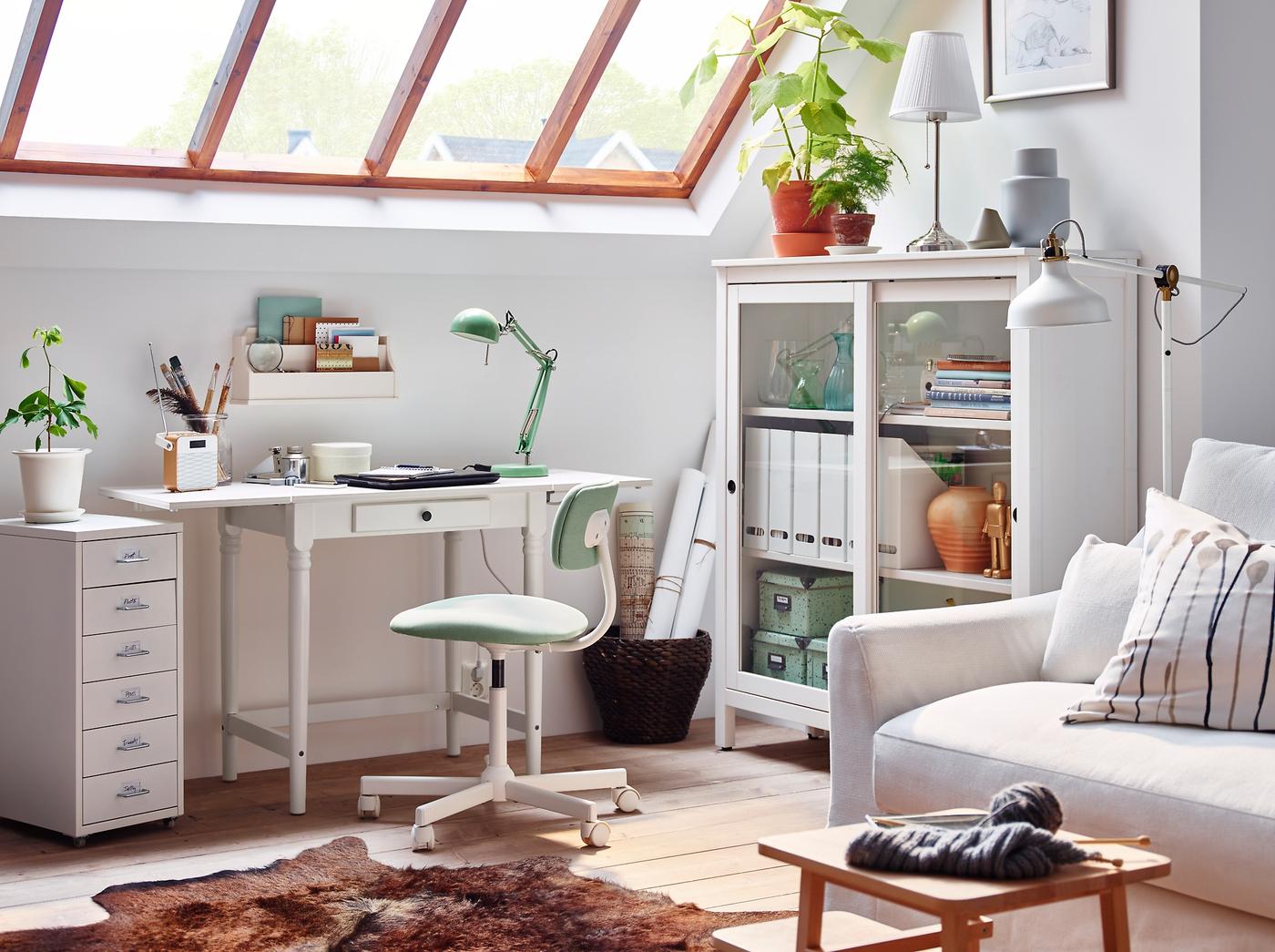 A traditional INGATORP desk in white in a sitting room with glass sloped ceiling.