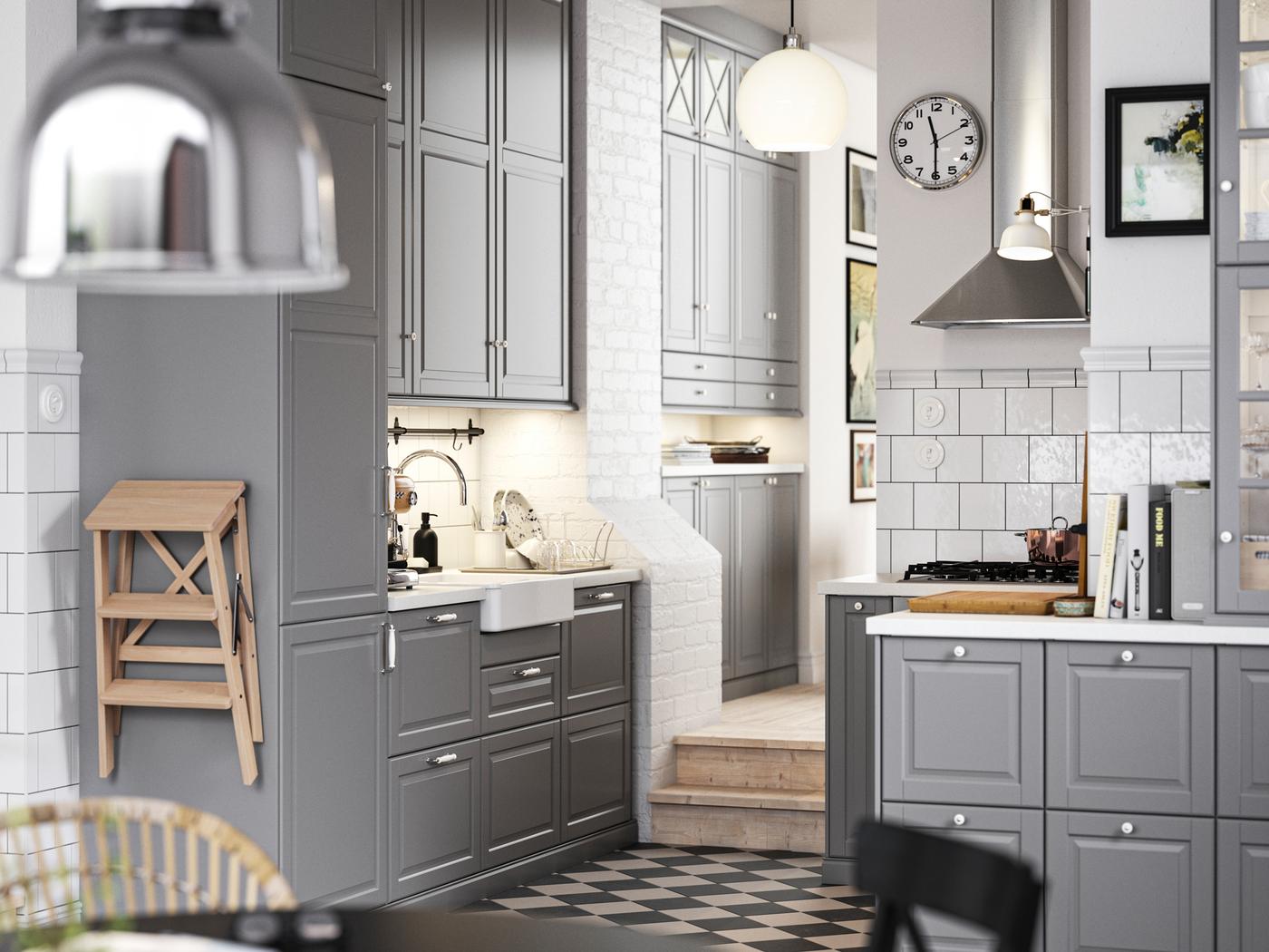 A traditional kitchen with a chequered floor, grey BODBYN kitchen fronts and white/light grey stone effect/laminate worktops.