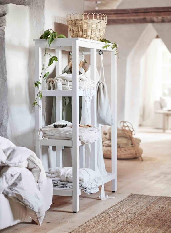 A traditional rattan basket sits on top of a white-stained open wardrobe.