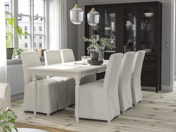 A traditional-style dining room with a white INGATORP table and six white BERGMUND chairs close by a window.