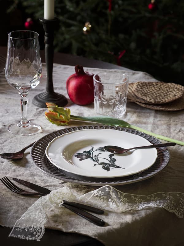 A traditional table setting with a white UPPLAGA dish in the centre on top of a blue plate.