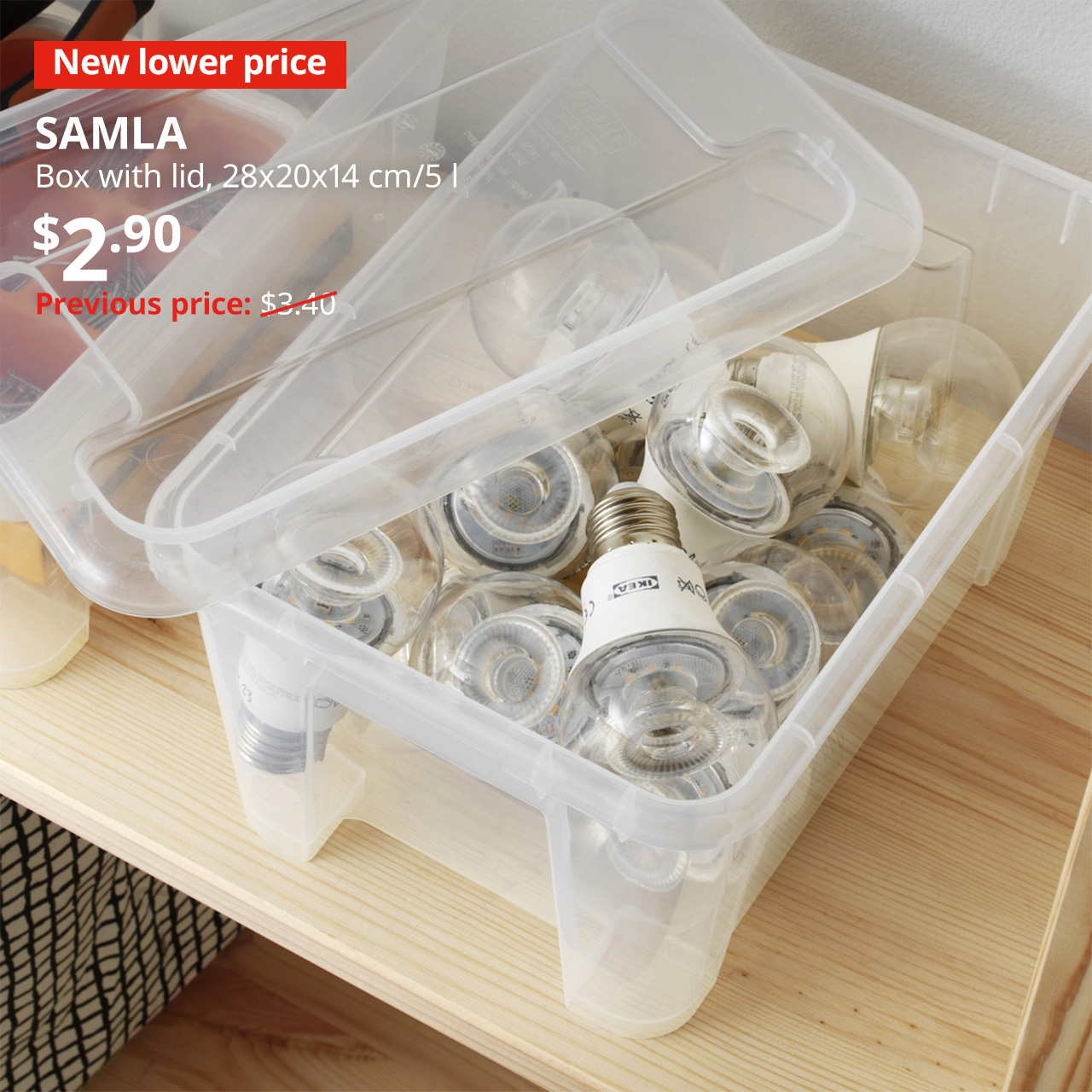 A transparent SAMLA box with a lid is used to store spare light bulbs. In the top left corner, a red tag with white text that reads "New lower price" is seen, followed by a white text overlay image that reads "SAMLA, Box with lid, 28x20x14 cm/5 l, $2.90, Previous price: $3.40".