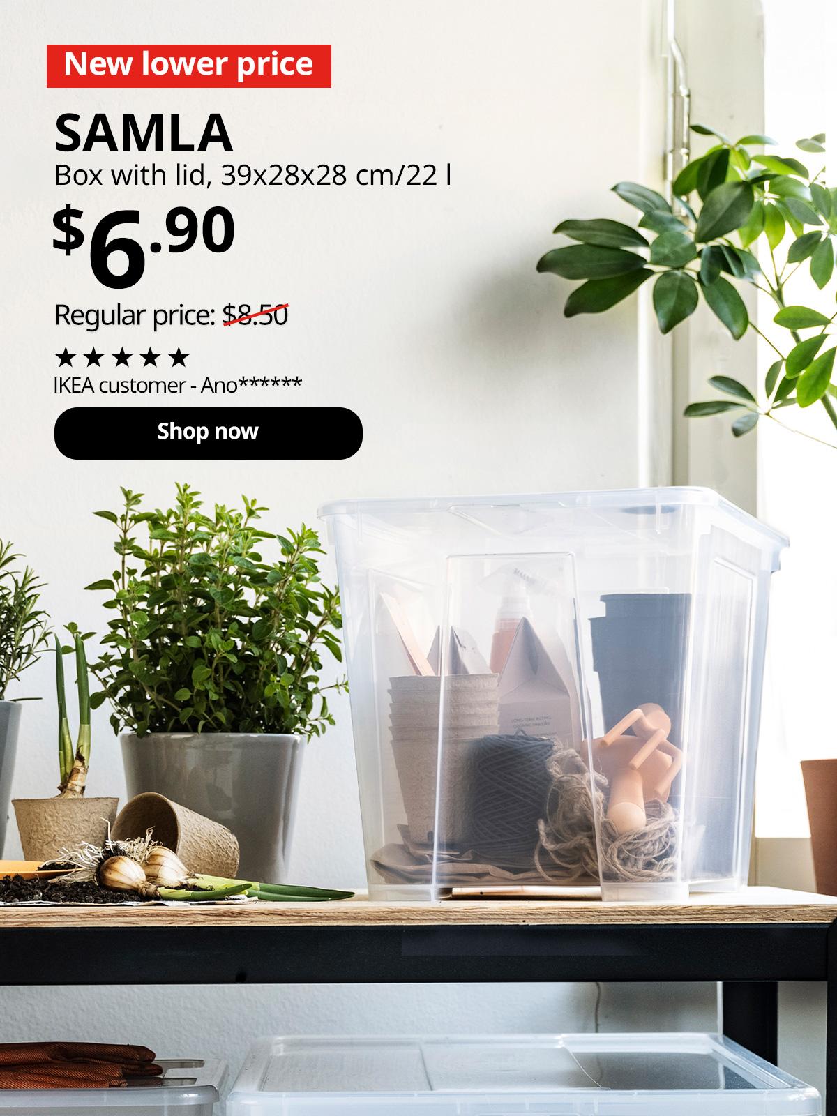 A transparent SAMLA box with lid is placed on a black/pine plywood BROR work bench in the service yard alongside a pot of plant. In the top left corner, a red tag with white text reads 'New lower price'. Accompanying white text displays: 'SAMLA, Box with lid, 39x28x28 cm/22 l, $6.90, Regular price: $8.50'
