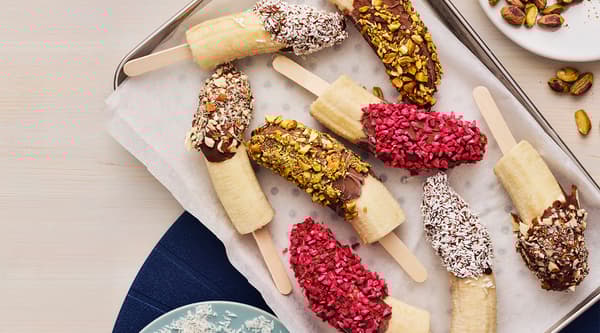 A tray full of chocolate dipped banana pops