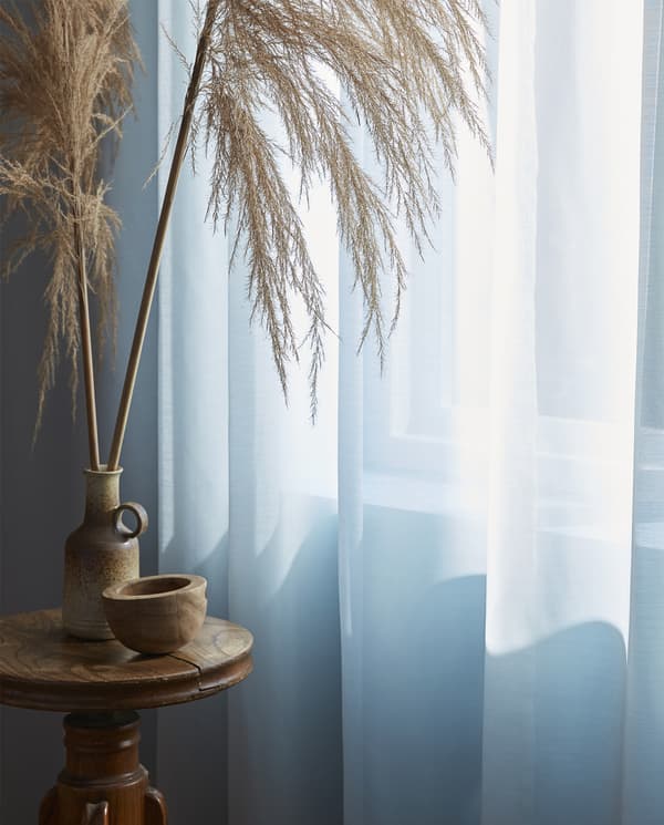 A türkiz színű HILJA függönyök és természetes anyagokból készült asztali dekorációk.