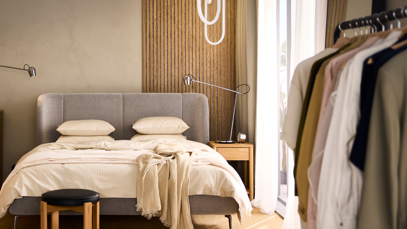 A TUFJORD double bed with storage with light beige NATTJASMIN bed linen and a VALLKRASSING throw on top.