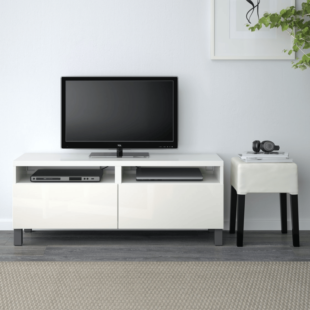 A TV stand with a flat screen TV against a white wall.