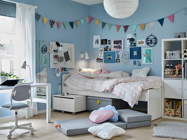 A tween bedroom with blue walls and white SLÄKT bed beside a white PÅHL desk and grey ÖRFJÄLL children's desk chair.