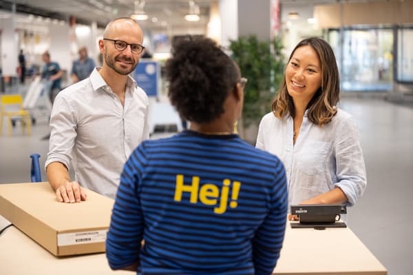 À un comptoir, une collaboratrice du service clientèle IKEA conseille des clients souhaitant retourner un produit IKEA.