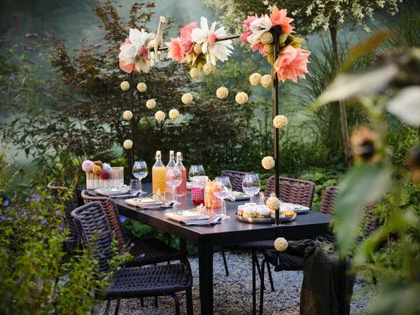 A una festa all’aperto, tavoli apparecchiati con tovaglie GULLMAJ, piatti UPPLAGA, bicchieri DYRGRIP e posate UPPHÖJD.