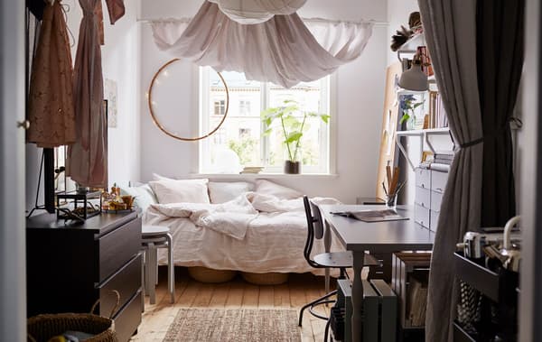 A university bedroom viewed from the entrance. Light-coloured fabric hangs from the ceiling.