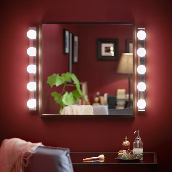 A vanity mirror is lit on both sides with a rown of bulbs.