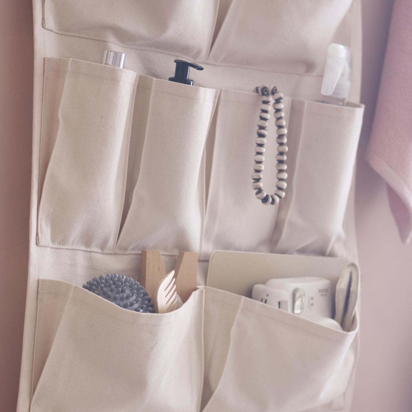A VÅRDANDE 100% cotton canvas wall organiser hangs on a wall, filled with bathroom accessories.