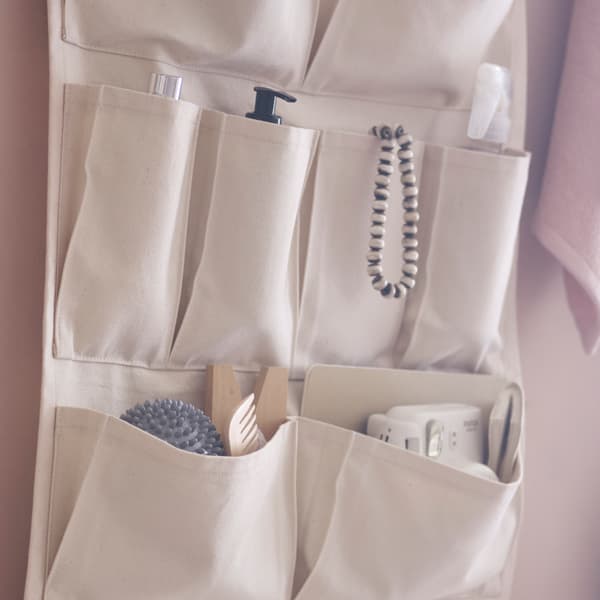 A VÅRDANDE 100% cotton canvas wall organizer hangs on a wall, filled with bathroom accessories.