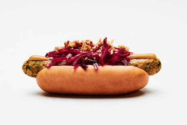 A veggie hotdog in a bun with pickled cabbage on top and toasted onion flakes. 