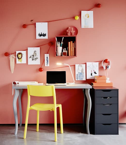 A very creative, brightly coloured workspace is decorated with illustrations hung above the desk.