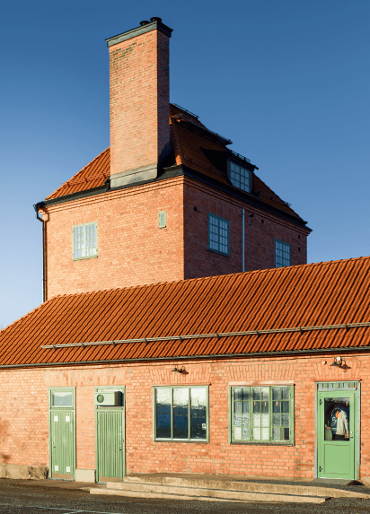 A view of the front of a building made with orange bricks, blue skies behind.