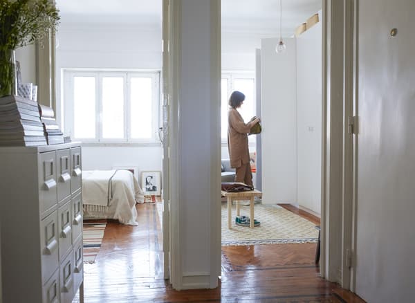 A view through the bedroom doors to Carolina opening her wardrobe.