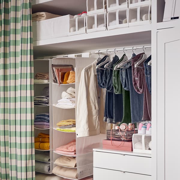 A VIHALS chest with 4 drawers with a hanging rail above it holding clothing and two SKUBB storage with 6 compartments.