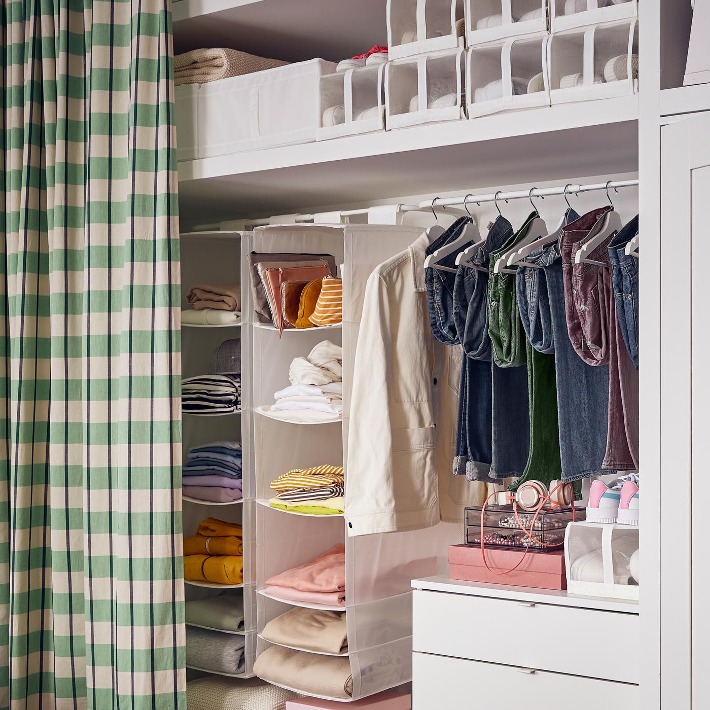 A VIHALS chest with 4 drawers with a hanging rail above it holding clothing and two SKUBB storage with 6 compartments.