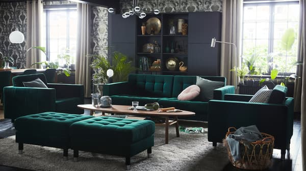 A vintage-style living room with a green velvet LANDSKRONA sofa, two armchairs and two footstools around a coffee table.