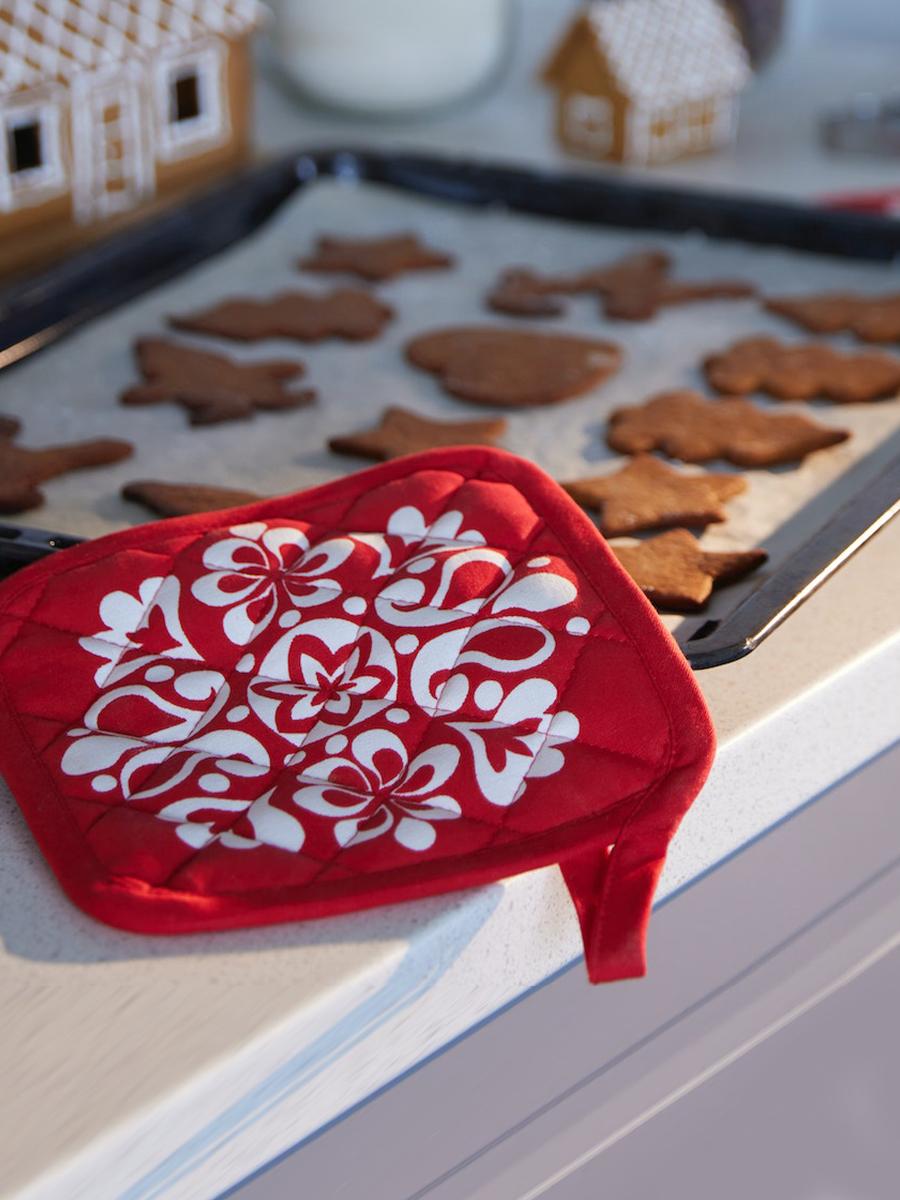 A VINTERFINT 2022 pot holder is placed nearby a baking tray filled with cut-out cookie dough.