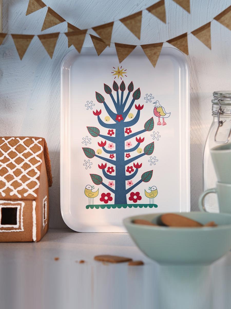 A VINTERFINT serving tray with scandinavian-patterned tree is propped against the wall in a kitchen.