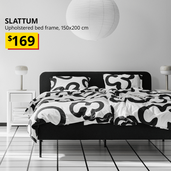 A vissle dark grey SLATTUM upholstered bed frame positioned against the wall. The text on the top left of the image with black text that reads: SLATTUM, Upholstered bed frame, 150x200 cm. Price at $169.