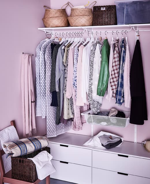 A walk-in closet is organized with drawers, hangers and baskets on the top shelf.