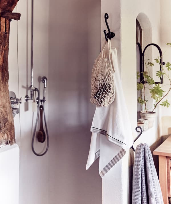A walk-in shower area and towels hanging on hooks.