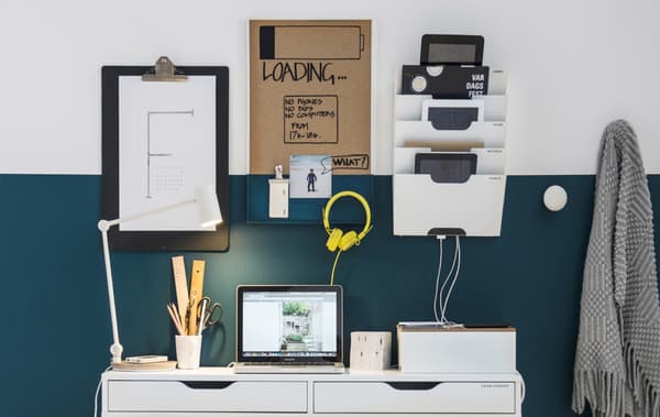 A wall made into a family charging station with a desk, newspaper rack and cable management box