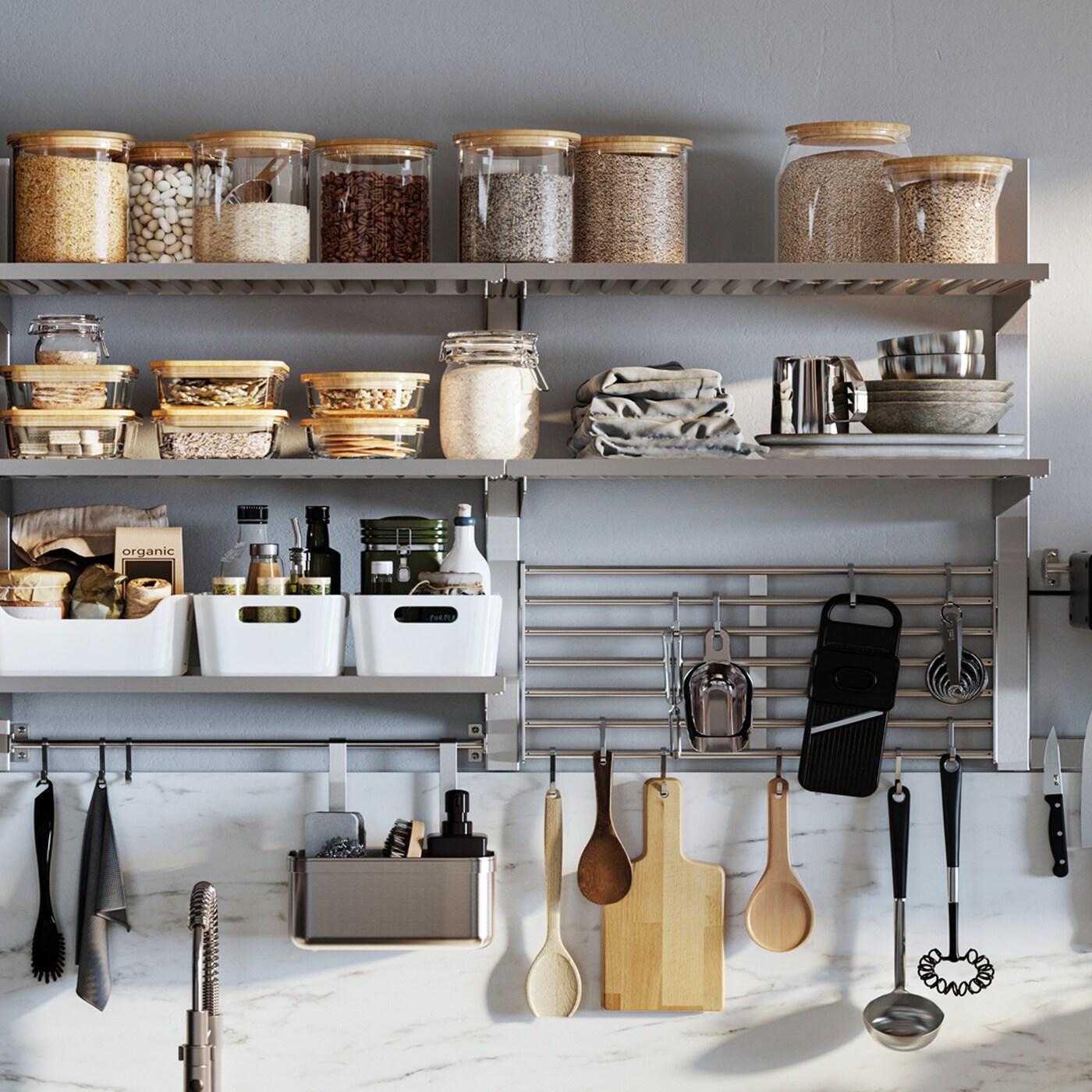 A wall-mounted KUNGSFORS kitchen storage combination with glass jars with lids, white storage boxes and hanging utensils.