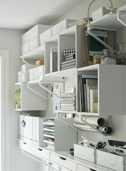 A wall of storage shelves, boxes and trays filled with office items.