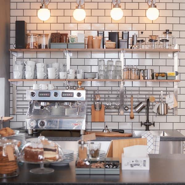 A wall shelf with two wooden shelves and KUNGSFORS wall rack with metal grids and hooks for hanging kitchen accessories.