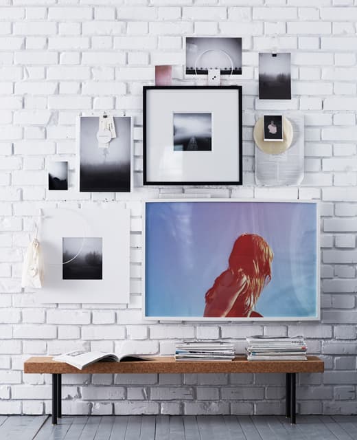 A wall with a combination of poster and photographs with and without frames.