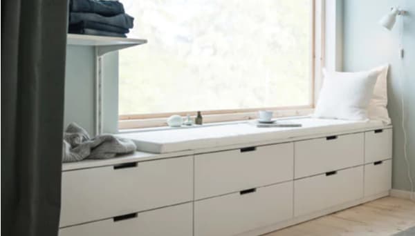 A wall with a window and a row of low bedroom storage made from modern, white chests of drawers