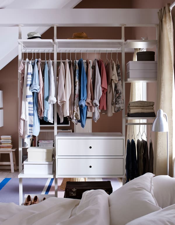 A wardrobe dividing two rooms, featuring clothes hanging and folded.