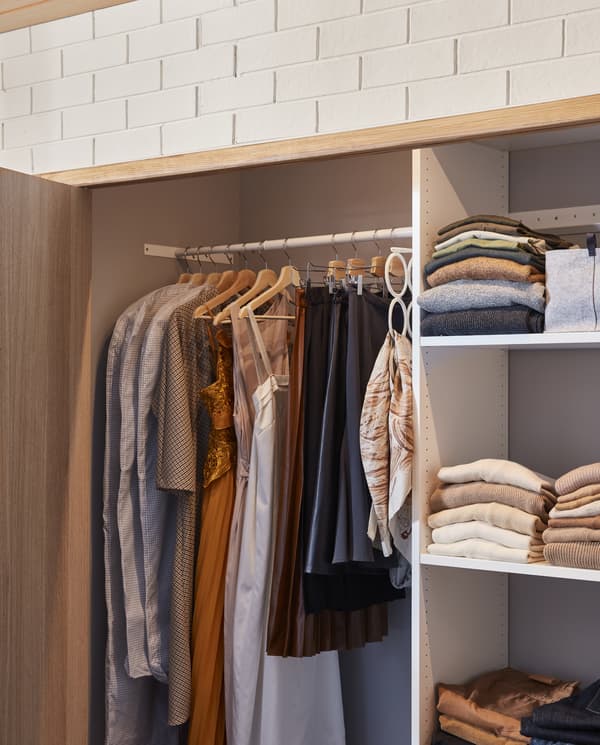 A wardrobe solution that consists of shelves and rails. Some clothes hang on the wooden hangers and some lie on the shelves.