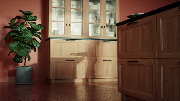 A warm-toned kitchen with VEDHAMN oak drawers and glass fronts; the kitchen cabinets are filled with crockery and glasses.