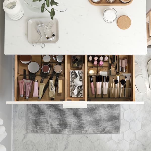 A wash-stand with a countertop in a marble effect. A drawer is open and inside are GODMORGON boxes that help organise makeup.