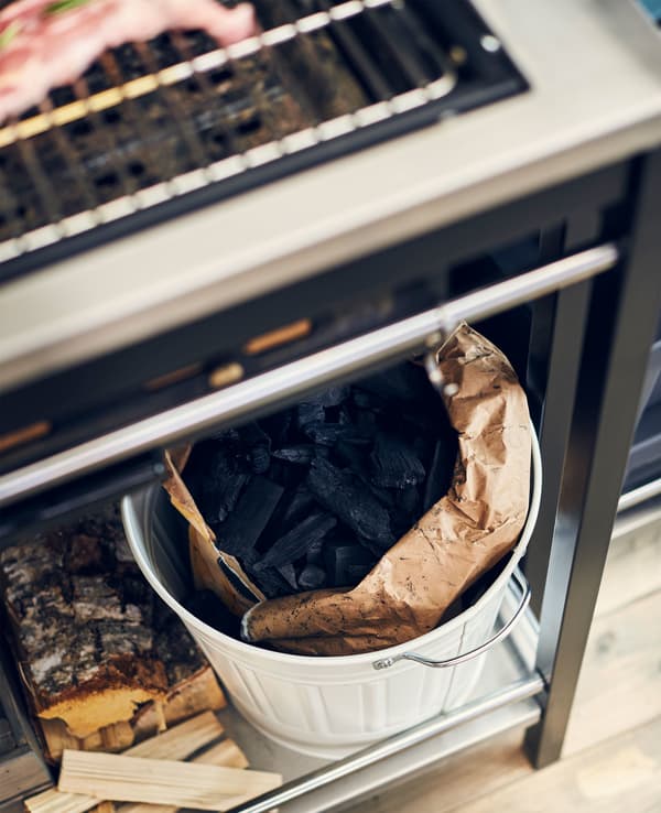 A waste bin with a bag of charcoal inside.