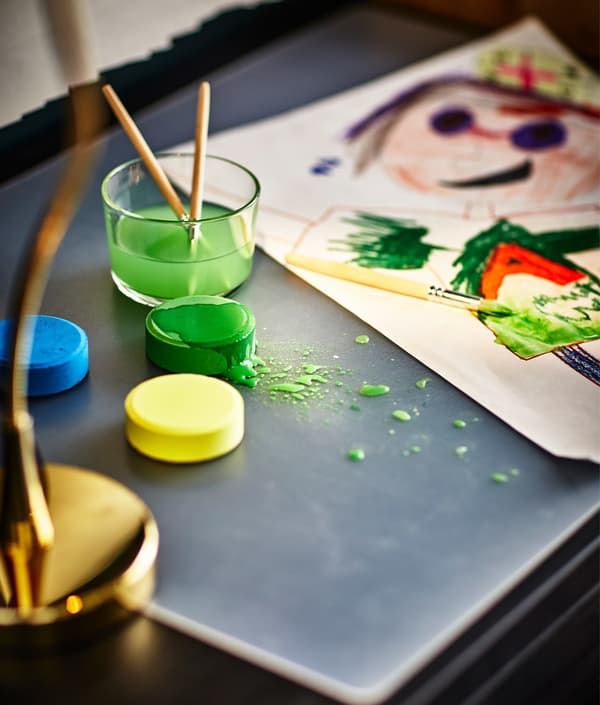 A watercolour painting being created at the desk with a few spills of green paint.