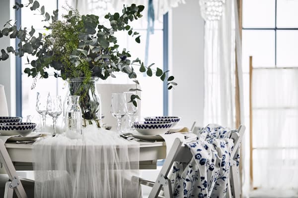 A wedding table with a floral centerpeice, blue fabric backed TERJE chairs with a  white traditional dining set. 
